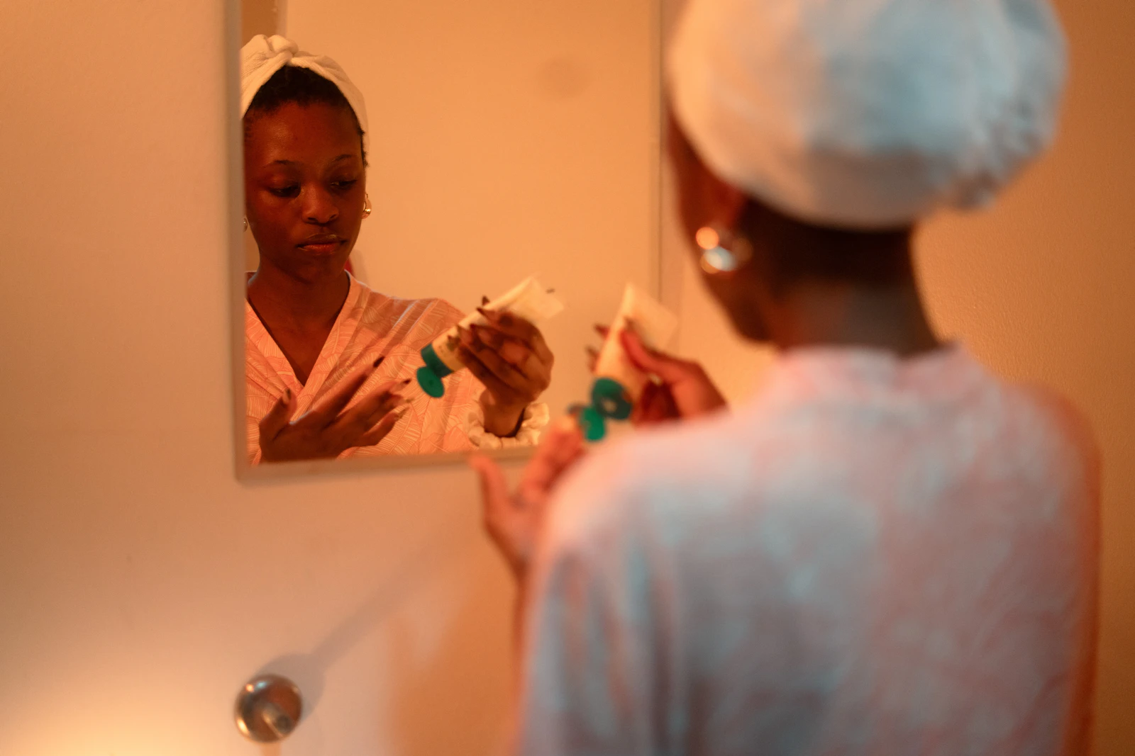 Woman applying a pea-sized amount of cream to her face in the mirror