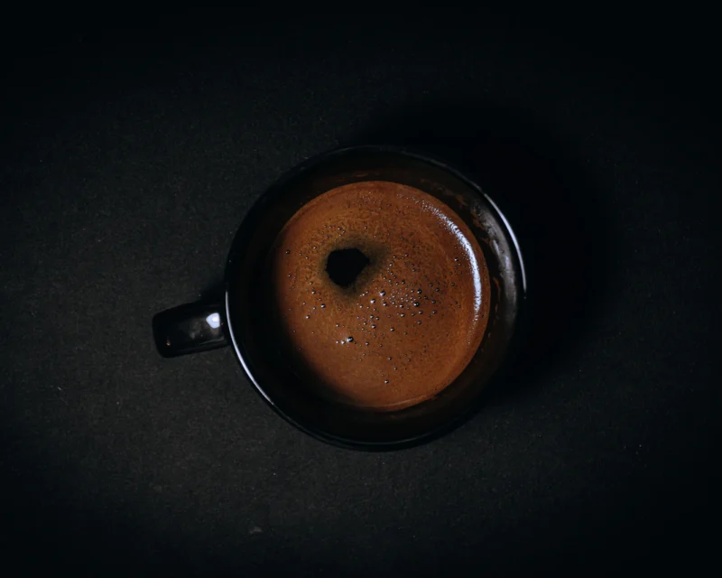 Black ceramic mug of dark mushroom coffee on a table